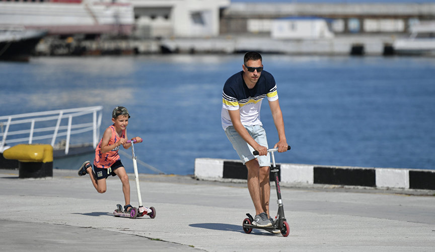 A man and a boy ride scooters in Yalta