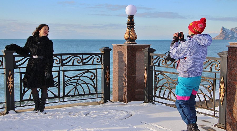 Tourists take pictures on the promenade of Sudak